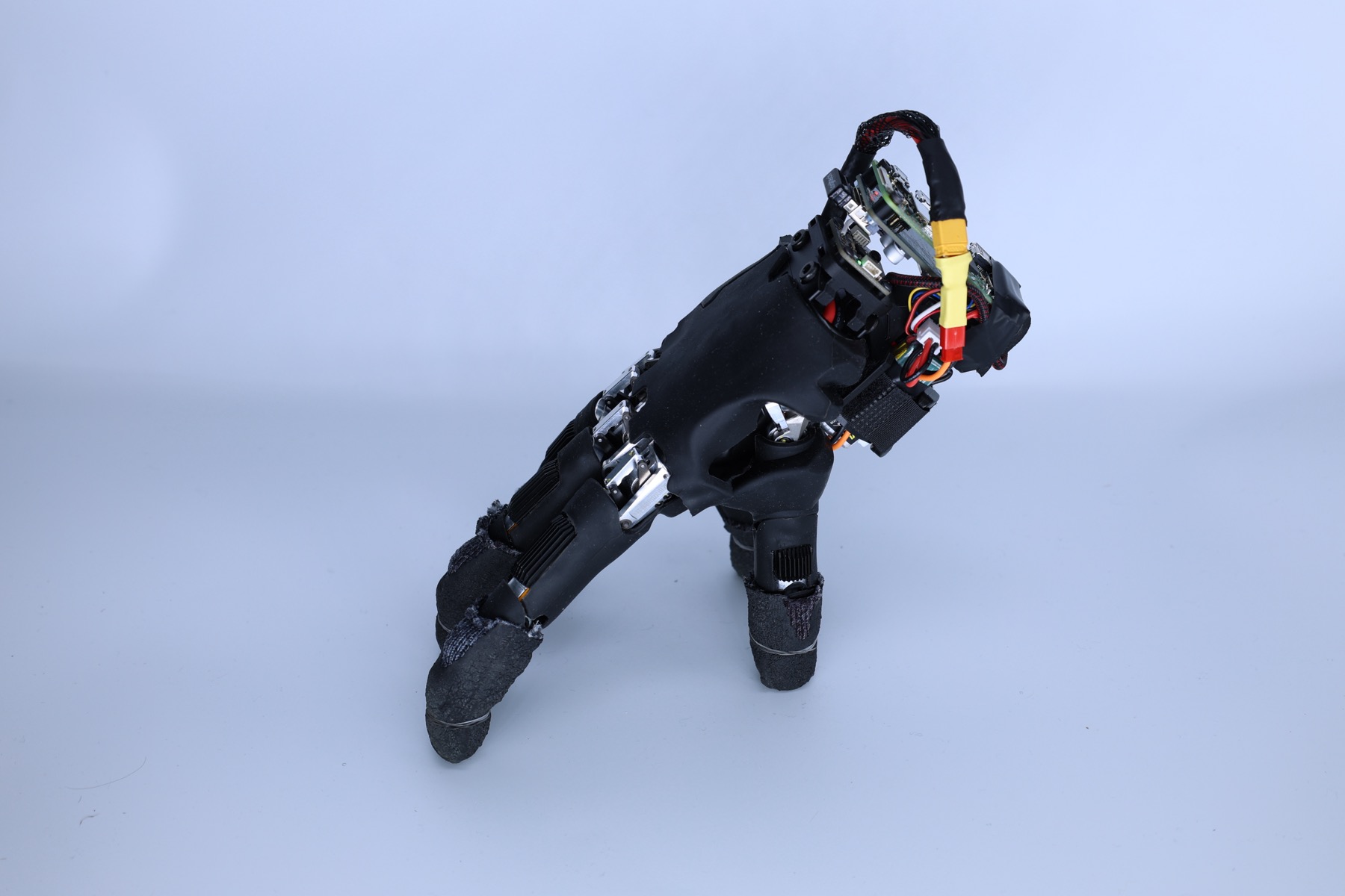 The self-supported WUJI hand standing on its fingertips, with battery and onboard computer mounted above the palm