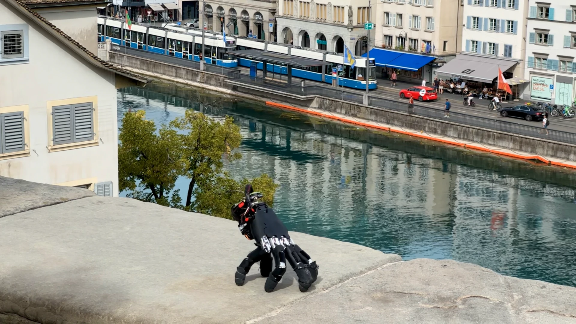 The robotic hand walking on weathered stone beside the river in Zurich